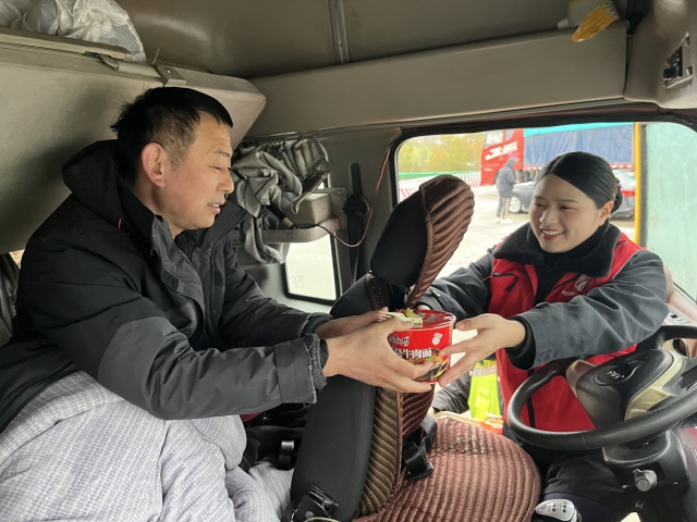 2月21日阜陽(yáng)處毛集站李方月在道口為滯留司乘提供簡(jiǎn)易餐食。.JPG